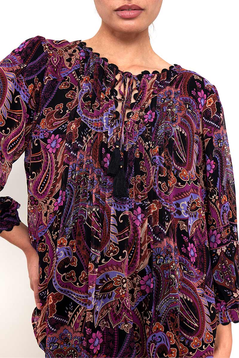 Detail shot. Model wears East Heritage Aubrie berry paisley printed pintuck blouse with black jeans and brown suede boots.