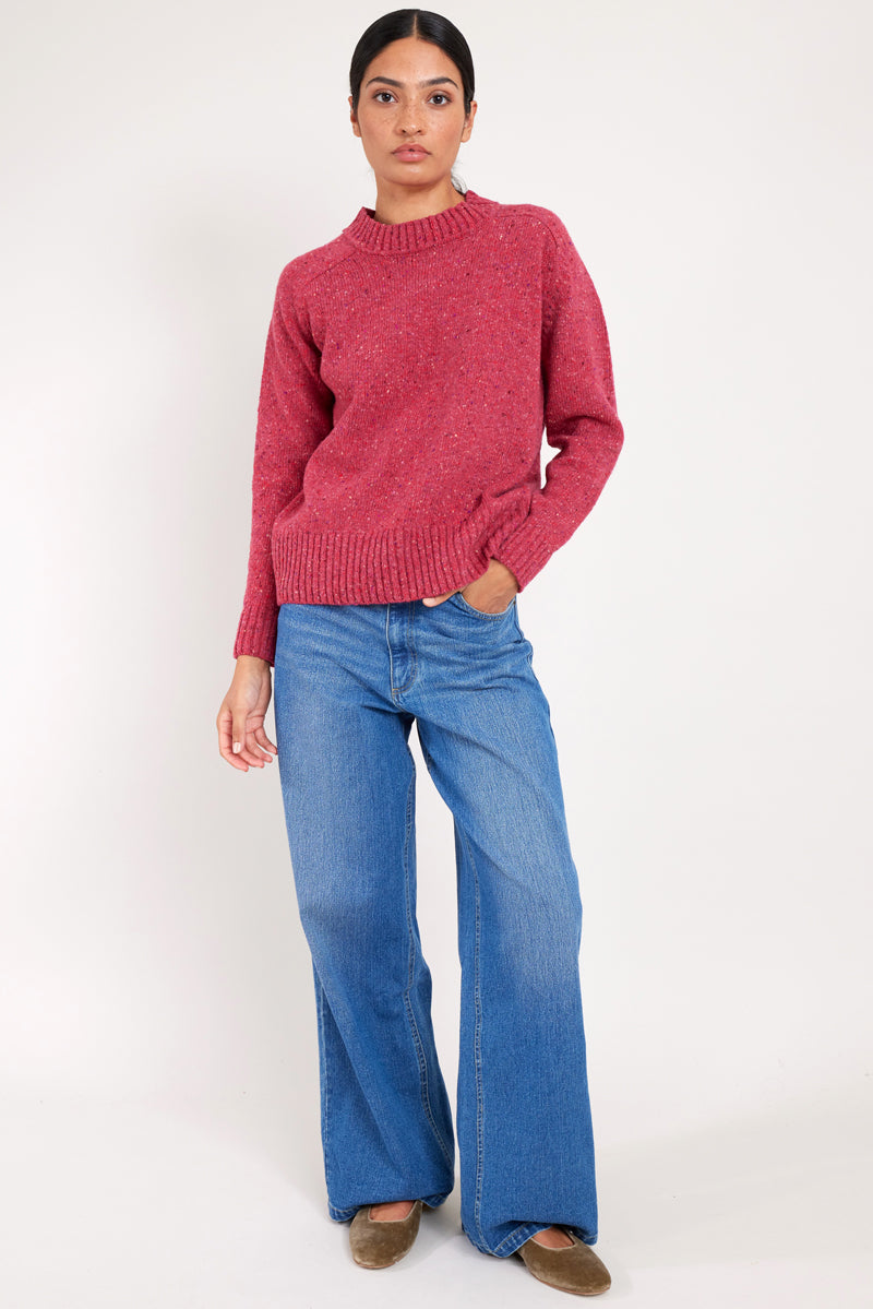 Model wears a raspberry colour merino wool jumper.